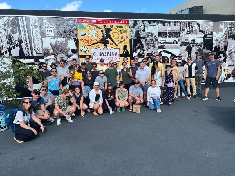 The Monte Carlo team poses for a group photo in front of a wall of Little Havana images.