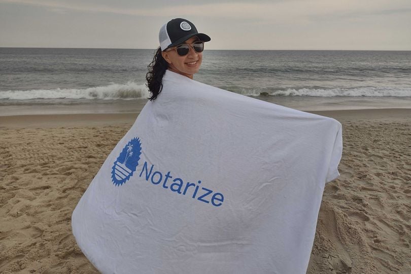 Notarize team member at the beach wrapping a towel with the company logo around her shoulders