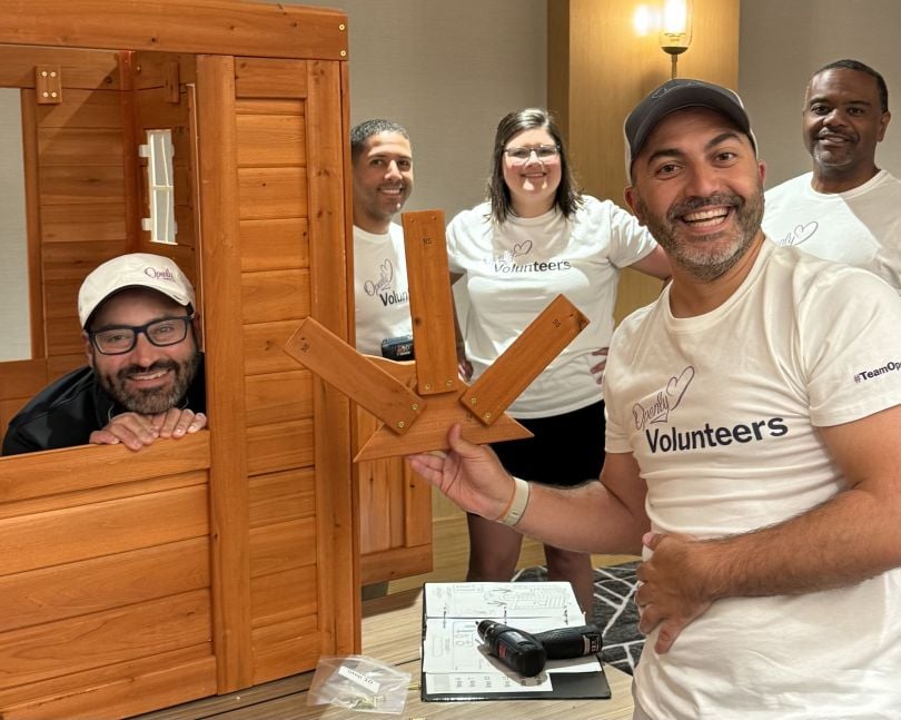 Five Openly team members pose for a photo while building furniture during a volunteering event