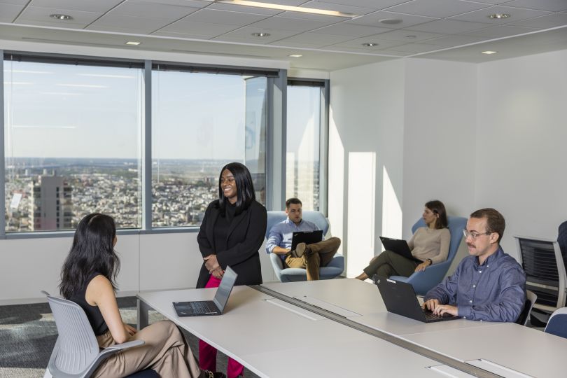 ZS team members working in open space, one woman standing and talking to another.