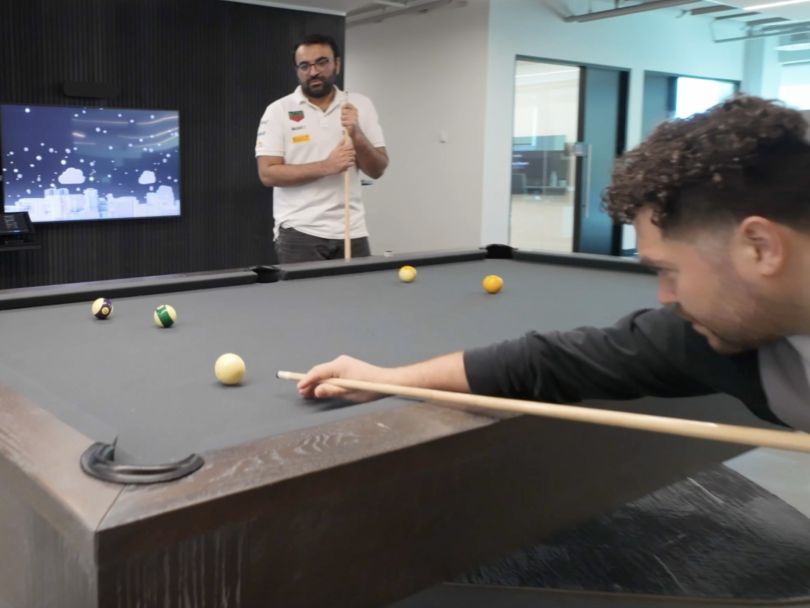 Two Own Company employees play pool in the company office.