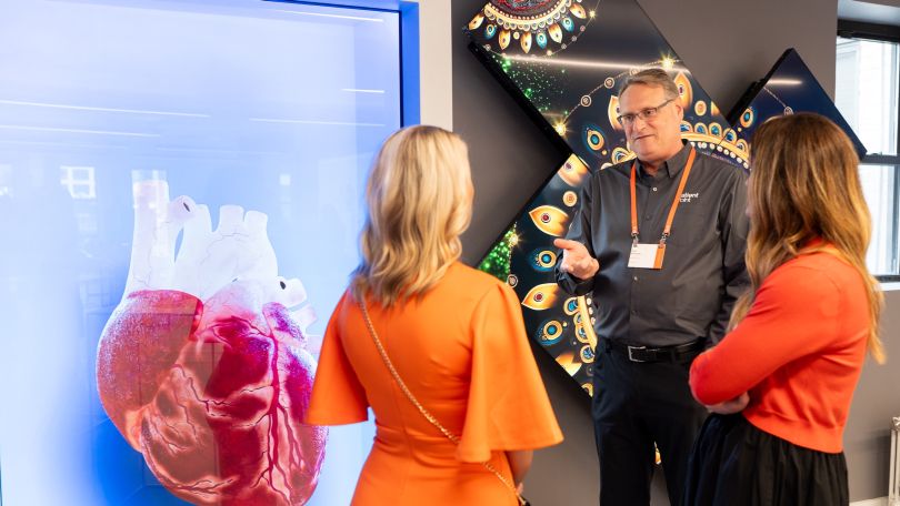 PatientPoint employees chat in front of a colorful wall decoration. 