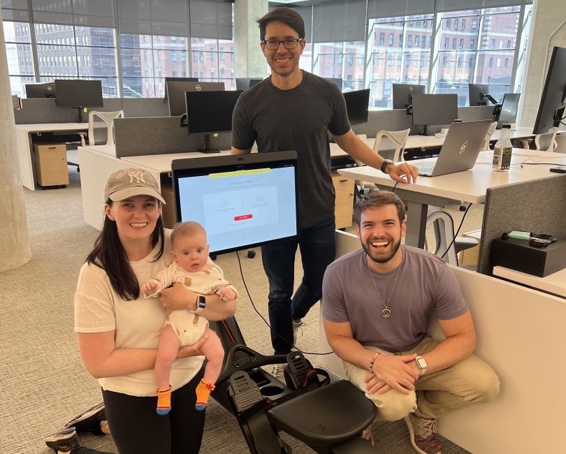 A photo of the Peloton team smiling in the office together. 