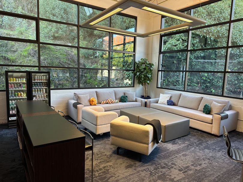 A lounge area with a couch is seated next to a window in Philo’s office