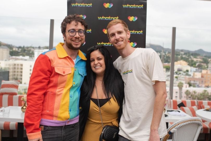 Three team members pose in front of Whatnot-branded banner at Pride event.