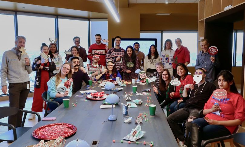 Fivetran team members holding holiday celebration photo booth props surrounding table.