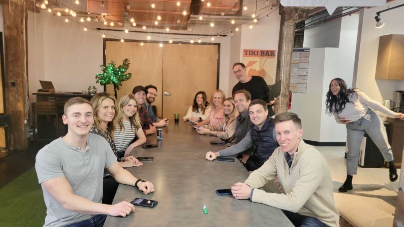 HealthJoy team members sit at a long conference table looking at camera and smiling