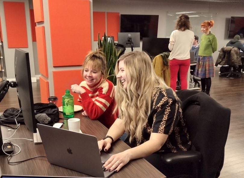 Two colleagues looking at a computer together smiling