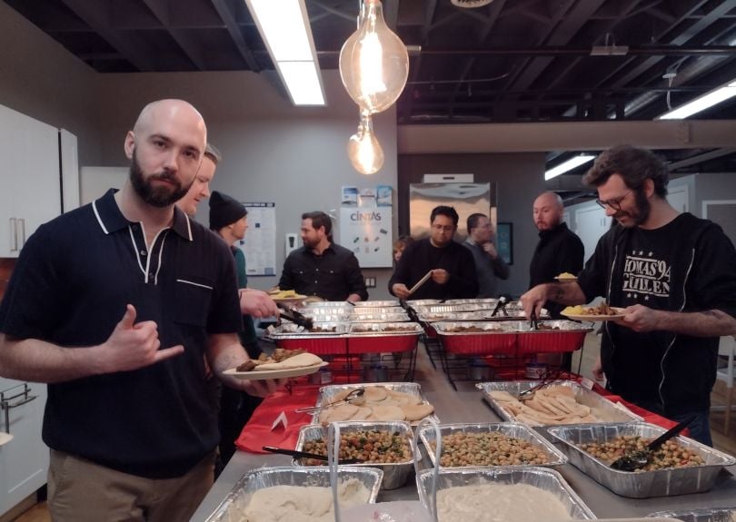 Team surrounds buffet of food at office kitchen