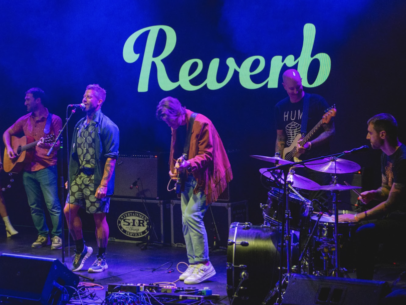 Reverb colleagues perform on stage together at an event