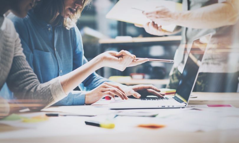 Image of two coworkers collaborating together in front of a laptop