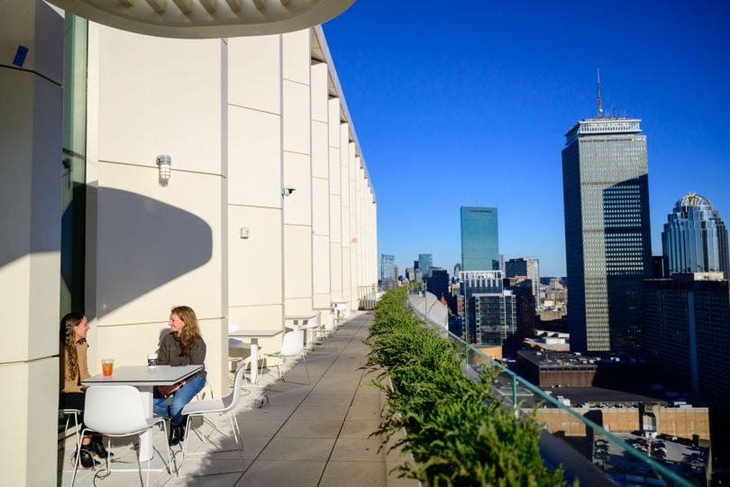 Two CarGurus team members meet at a table on the balcony of the company’s new global headquarters at 1001 Boylston Street overlooking Boston’s Back Bay neighborhood.