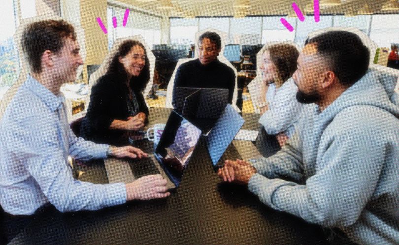 Simply Business team members gathered at table with laptops in office