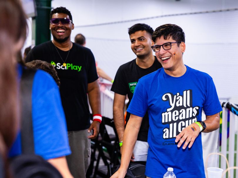 SciPlay team members laughing together, wearing company-branded shirts during Pride Month event.