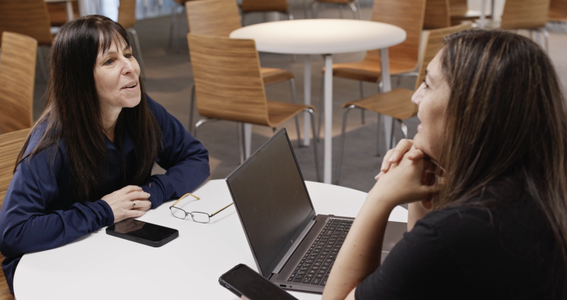 Debbie Taylor and Marcela Fernandez Reed meet over a conference table at DIRECTV's offices