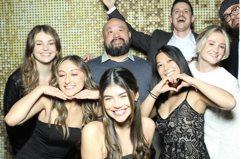 Cie employees pose for a group photo in front of a sparkling wall. 