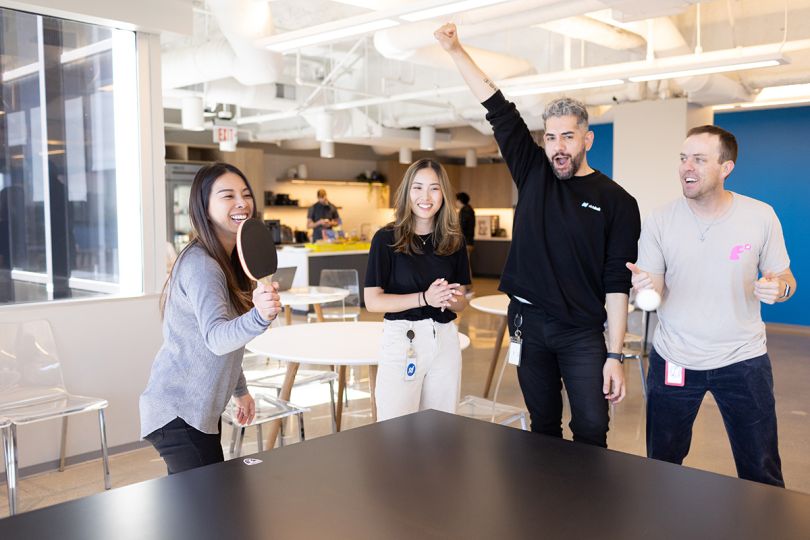 Slickdeals coworkers playing ping pong in the office breakroom