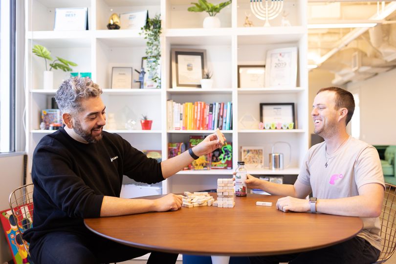 Slickdeals coworkers sitting at a table playing Jenga in the office