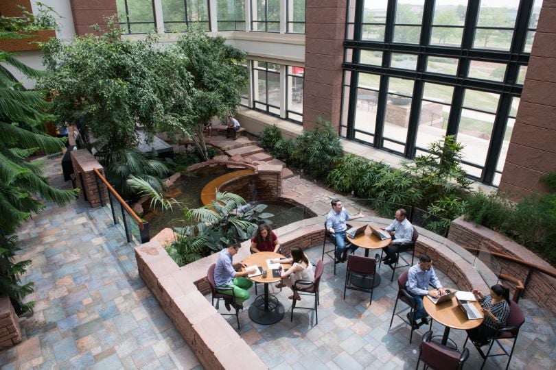 Overhead photo of seven team members working together in small groups in a communal, atrium space within EchoStar’s office.