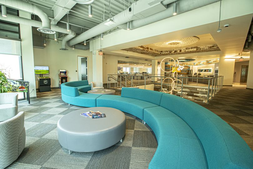 Photo of Aristocrat's Summerlin campus space, modern seating area with circular couch and full-sized arcade games along the wall