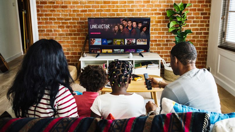 Family sitting on a couch with the Star+ interface on their television