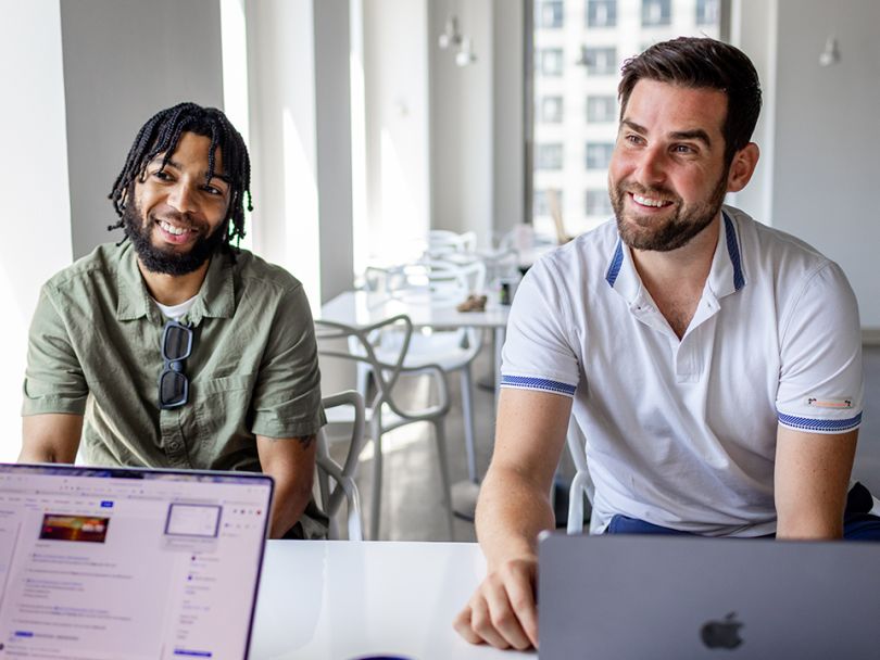 Two Productive Edge team members sitting at a table and smiling.