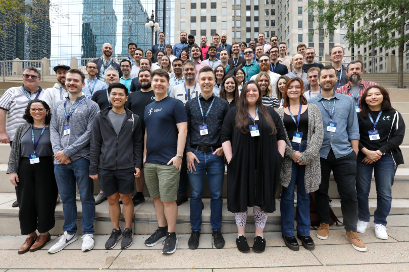 Large group photo of Tegus team on outdoor steps amid city buildings. 