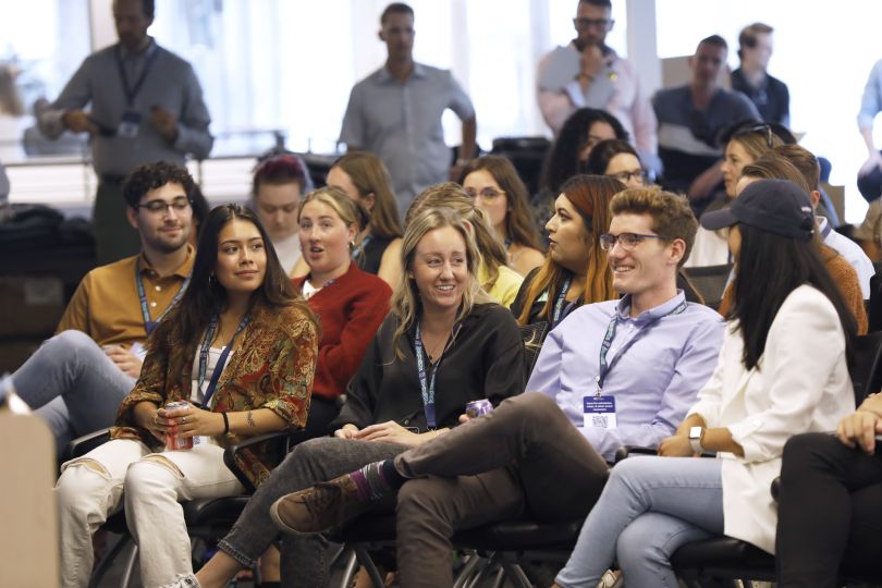 Candid photo of large group of Tegus team members sitting in rows waiting for a presentation to begin, talking and smiling. 