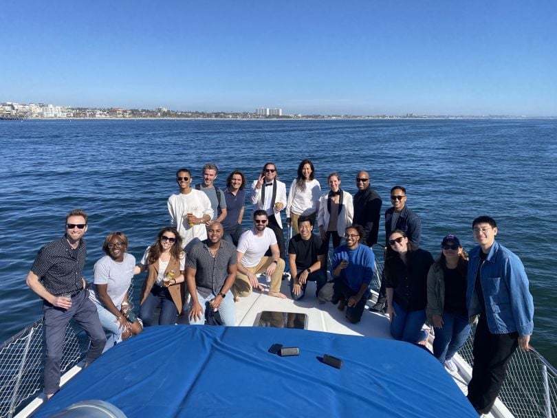 Employees from The Black Tux stand together on a boat that is on the water