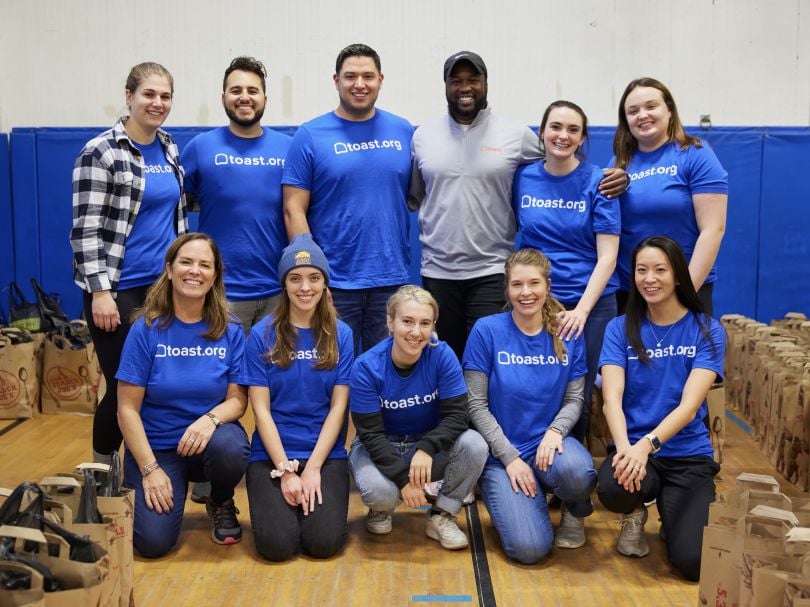  Toast employees in matching company swag pose for a group photo at a volunteer event.