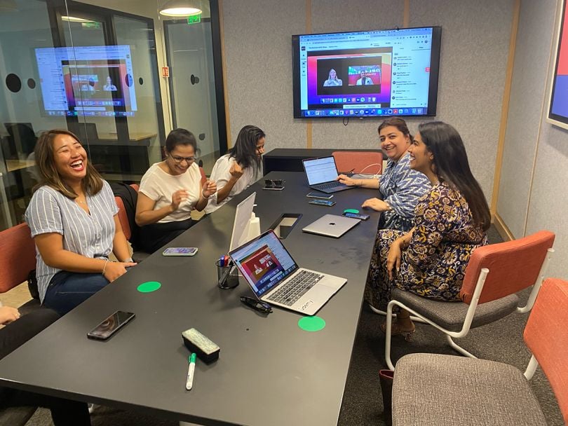 Udemy team members smiling and laughing around a conference table in the office