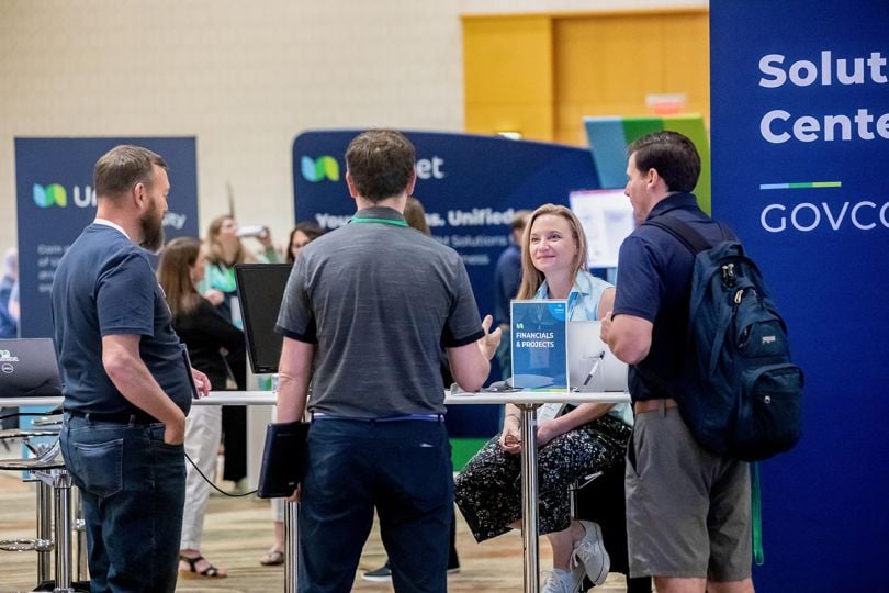 Unanet team member talking with people at the company booth at an expo