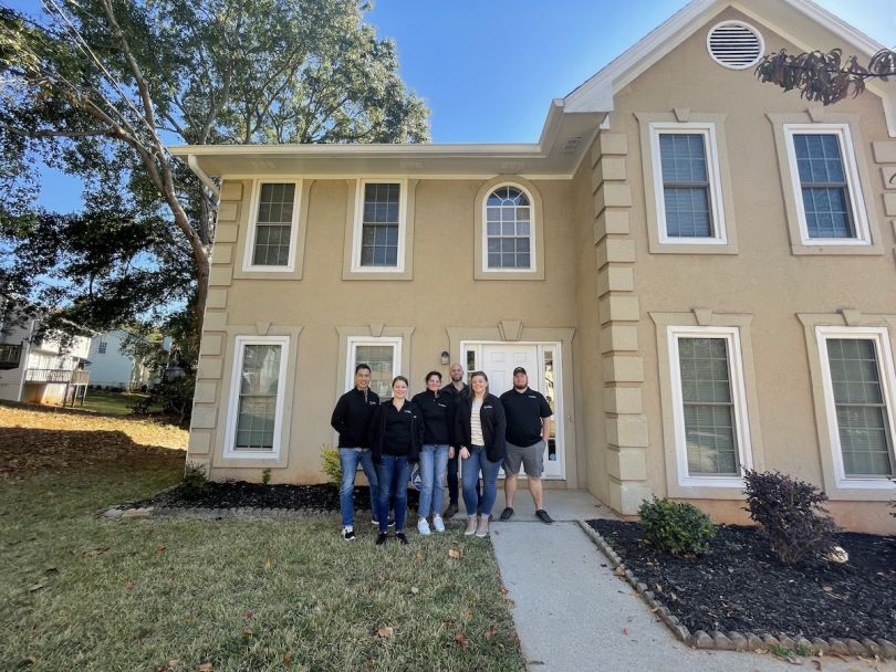 Up&Up team members pose outside of a rental home