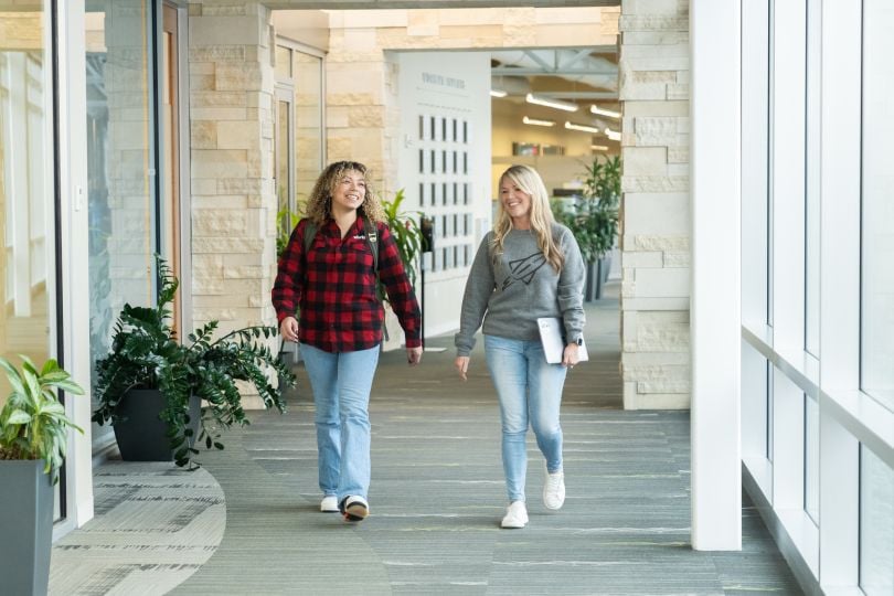 Two Workiva team members walking in hall together, smiling