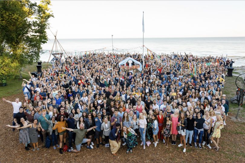 A large group of Wise employees stand together next to a lake