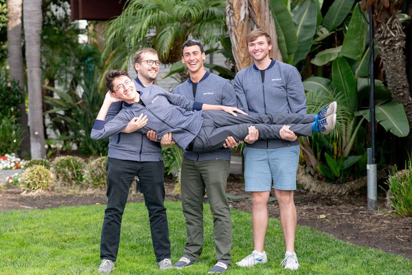 Three Yembo colleagues holding up a team member