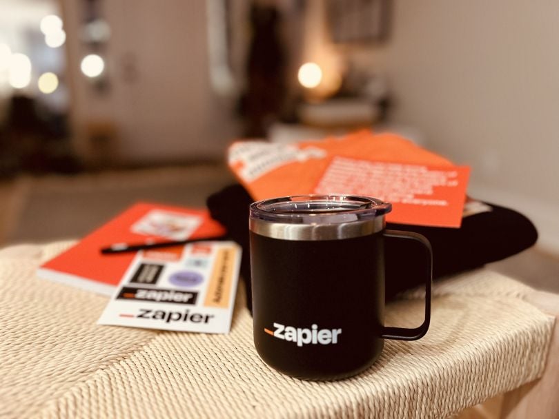 Zapier-branded merchandise, including a mug and notebook, laid out on a table