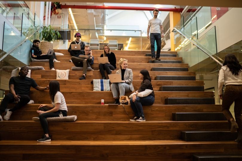 Members of the Braze team sitting on stairs in the office talking and working.