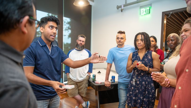 A group of Advisor360° employees stand talking with one another in the office. 