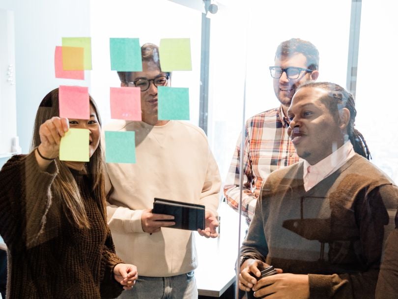 FOURKITES team members looking at colored sticky notes on a glass wall.