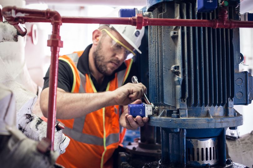 A technician installs an Augury device on a piece of equipment.