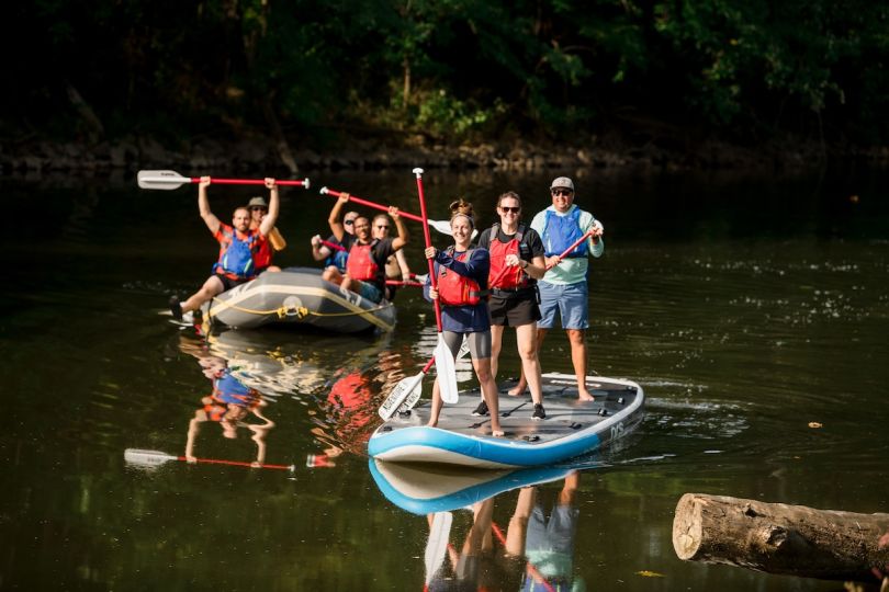 AWeber team members river raft and paddle board at a company retreat. 