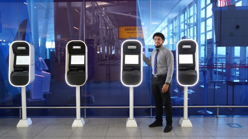 Man standing next to a CLEAR kiosk at an airport