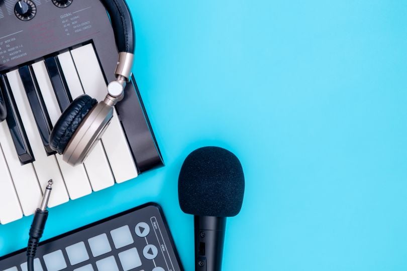 piano keyboard, microphone and headphones on blue background