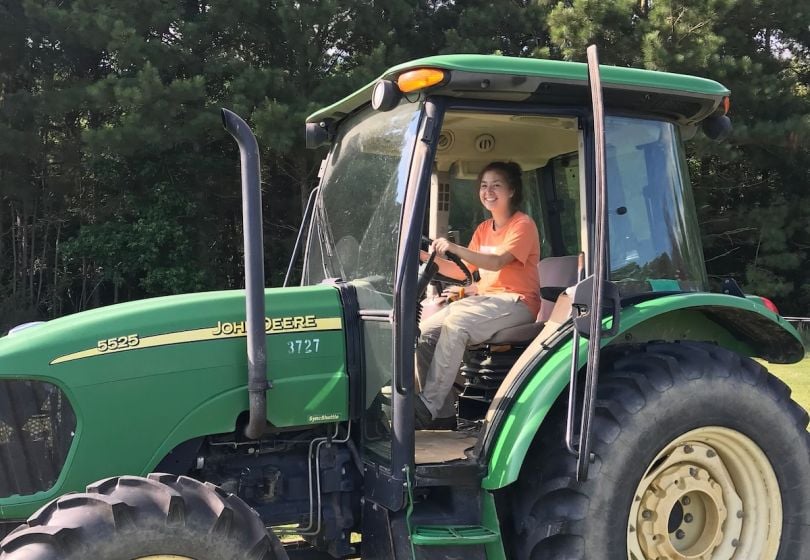 A Carbon Robotics team member poses for a photo inside a tractor. 