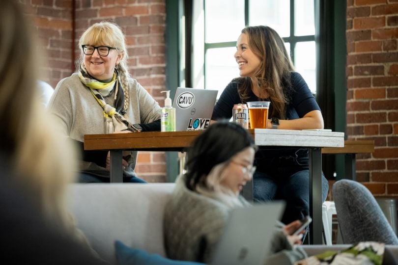 Two Cogo Labs teammates sitting together at a table smiling