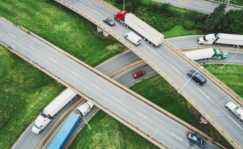 Trucks move through a busy highway interchange.