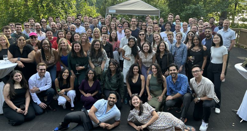  Large group of Garner Health employees pose for a photo outdoors, with trees and a pop-up tent in the background.