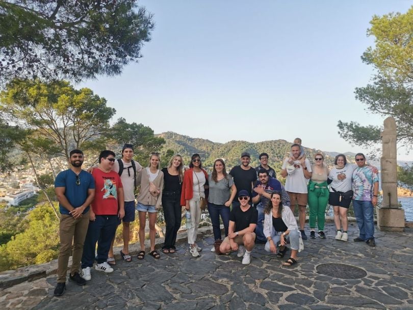 The Commercetools engineering team stands on a terrace overlooking green hills and water.