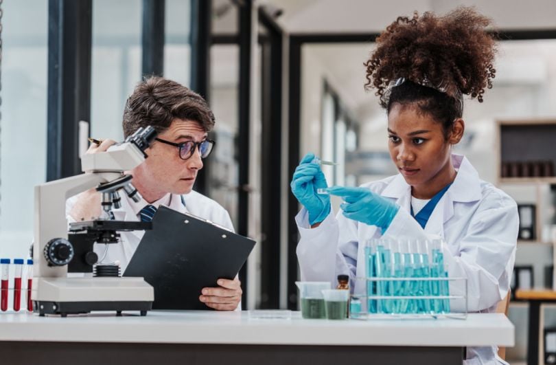 Two scientists engaged in research in a laboratory, working together near a microscope and test tubes.